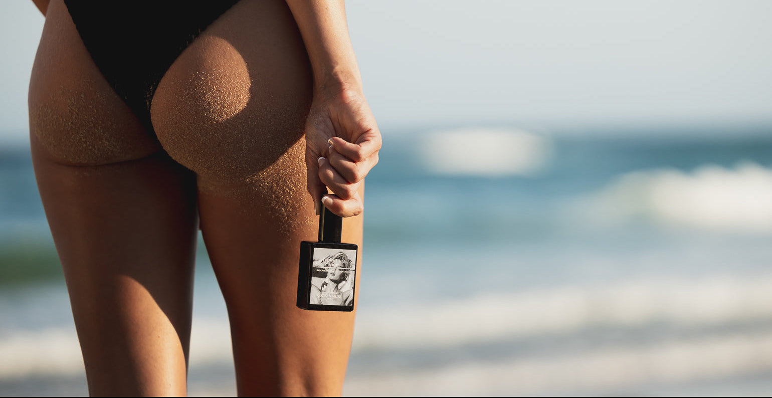 Woman holding Ocean Muse Hydrating Mist on a beach, showcasing a hydrating facial mist for refreshed and hydrated skin.